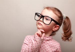 Cute kid girl in glasses thinking and looking serious